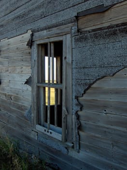 View through the window of an abandoned farmhouse in a field.