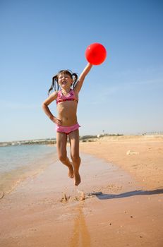 Girl jumping with balloon on the beach