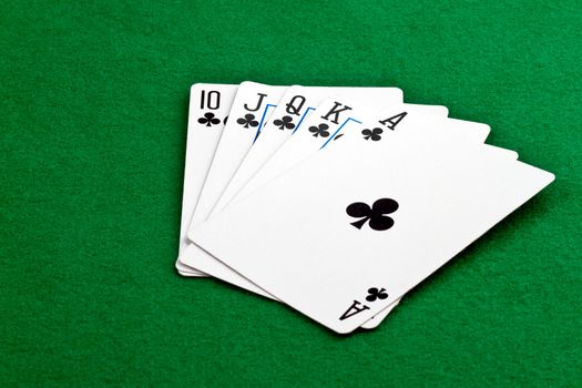 Royal Straith Flush poker hand with clubs on green felt