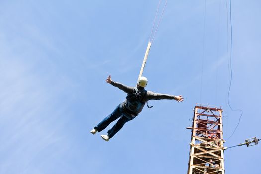 Silhouette of a man jumping with a rope from the derrick