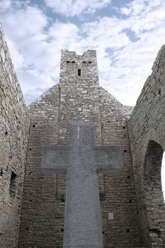 a celtic cross in the shadow of old ruins