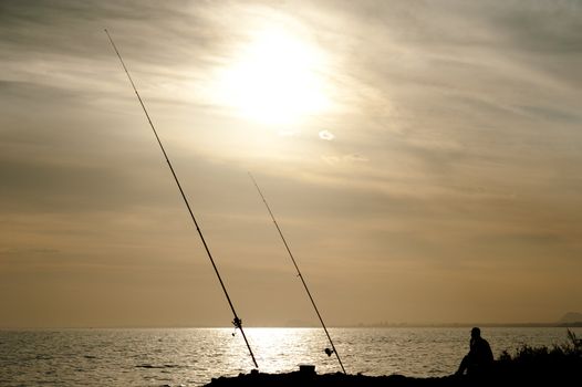 Silhouette of an angler in a sunrise landscape