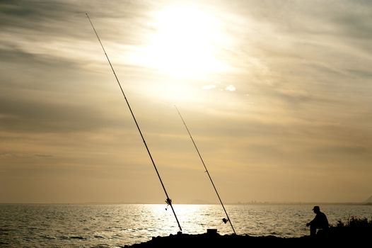 Silhouette of an angler in a sunrise landscape