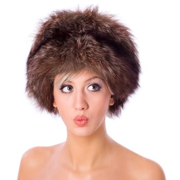 Young woman wearing fur hat making funny face isolated on white