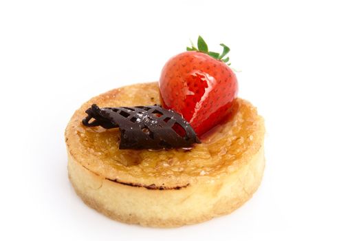 A delicious baked custard tart. Decorated with a strawberry and a chocolate curl. Shot on white