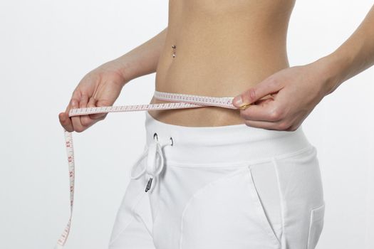 Slimming woman measuring her waist, the concept of growing thin. 