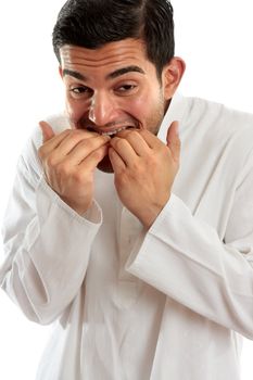 An ethnic man hunched over and  biting fingernails.  He may be scared or have anxiety, stress or other fears or worries.  White background.