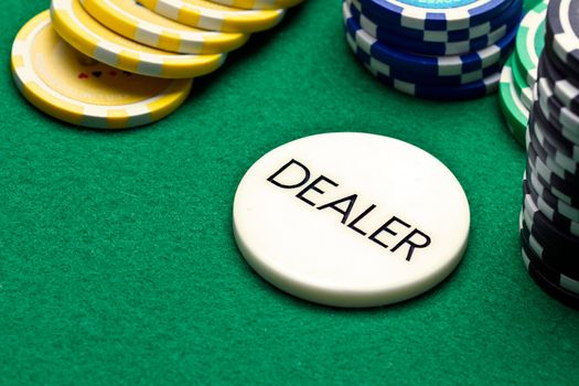 Poker dealer button and chips on green felt