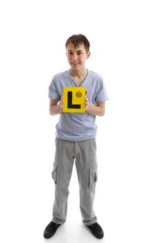 A teenage boy holds  L learner plate and smiling.