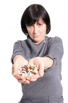 Aged woman holding a pile of pills and capsules in her hands