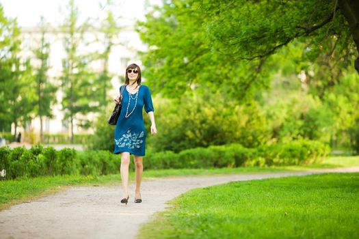 Hurrying woman walking fast trough park on a date