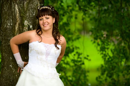 Happy Bride smiling near summer tree outdoors 