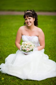 Happy Bride holding bouquet and smiling outdoors