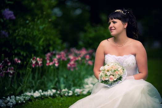 Beautiful brunette Bride in summer park looking away