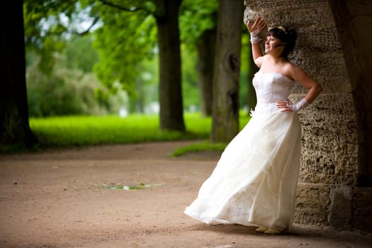 Beautiful brunette Bride in summer park looking away