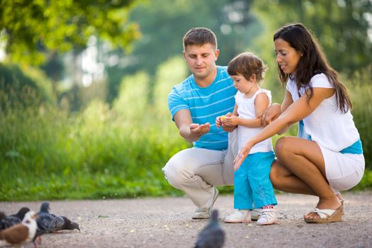 Happy Family feeding pigeons in summer park