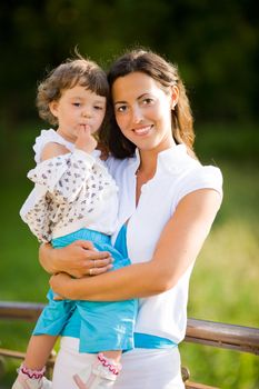 Happy mother holding one year daughter summer outdoors