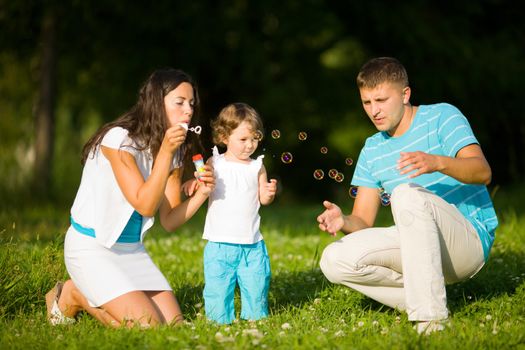 Happy Family making soap bubbles outdoors summer