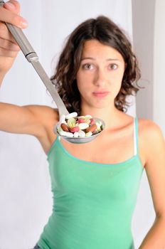 Shot of cute girl with spoon full of pills. Concept shot for alternative medicine