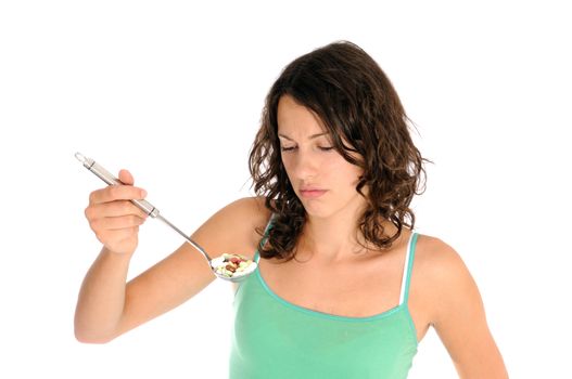 Pretty young woman holding spoon with pile of pills looking skeptical. Concept shot for drug abuse or alternative medicine.