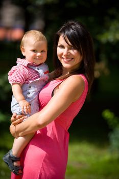 Happy mother holding one year son summer outdoors