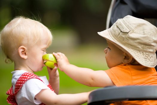 Two kids with apples outdoors looking after each other
