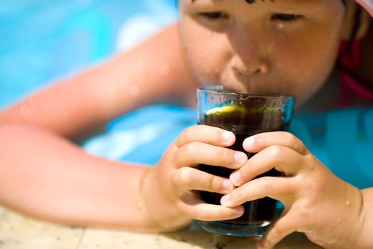 Child holding cola drink focus on glass and fingers
