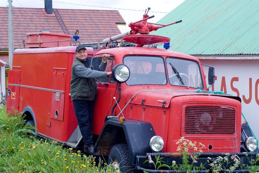 The man is on an ancient fire-engine with a lantern