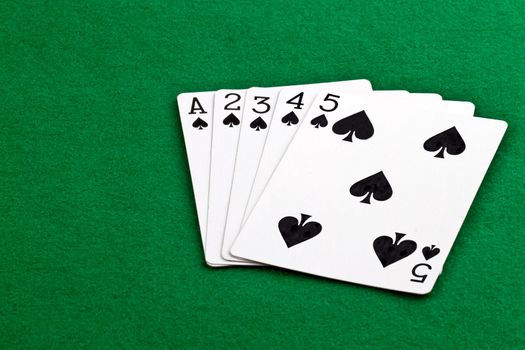Poker hand with a straith flush of spades on green felt