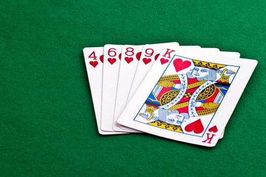 Poker hand with a flush of hearts on green felt