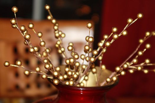 Attractive Christmas table centerpiece with gold holly berries. Dining room chair faded in the background. Holiday decoration for the winter season.