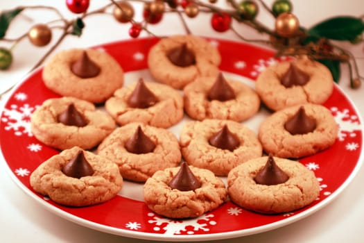 Tasty peanut butter cookies with chocolate kisses for the holidays. Christmas dessert on a red and white snowflake dinner plate. Holiday treats for the season.