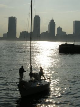 yacht silhouette on Hudson river, New Jersey buildings in distance, photo taken from Manhattan 