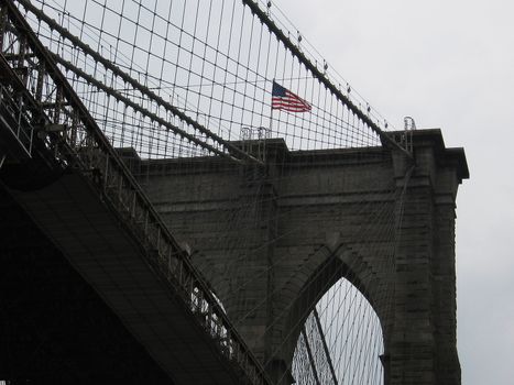 detail photo of brooklyn bridge in new york, american flag on top of it