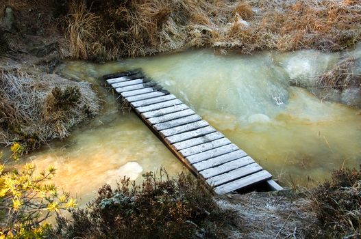 A wooden bridge over an icy stream