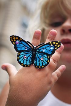 A little girl holding up a butterfly ring