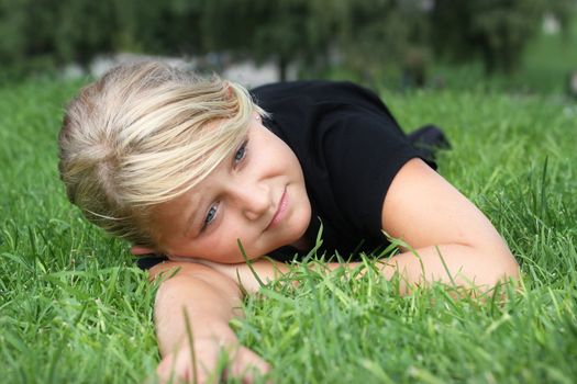 A young girl relaxing on green grass