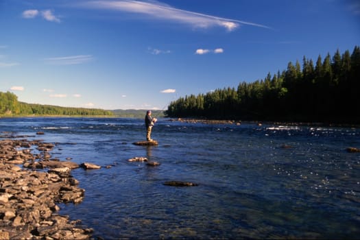 A man fishing in a river in sunny day