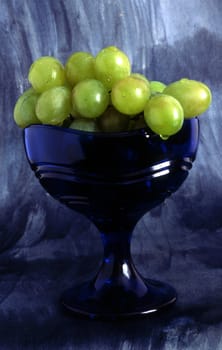 A glass of grapes on painted background