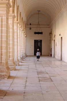 An old lady is walking through an old convent passage