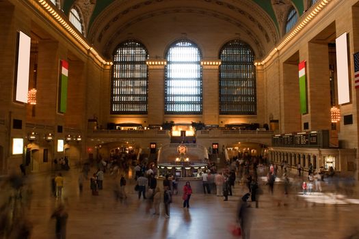 Time lapse photo of blurred people walking through Grand Central Terminal train station in New York City with one recognizable woman standing alone in the center.