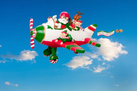 Santa Claus flying his airplane with Happy Holidays banner in the sky with his elves and Rudolf the Red nosed Reindeer.