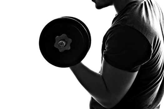 Back lit silhouette of a young man lifting weights in black and white.