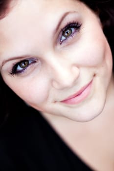 Close up of a beautiful young womans face with a friendly smile. Shallow depth of field.
