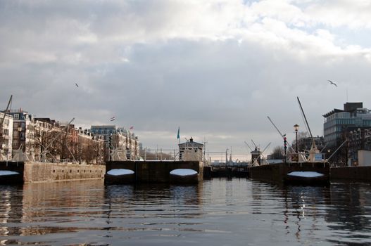 Sluices with riverside houses snow covered in Amsterdam, Netherlands