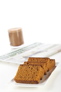 Dutch breakfast cake, often spiced with cloves cinnamon and nutmeg. A coffee and newspaper in the background.