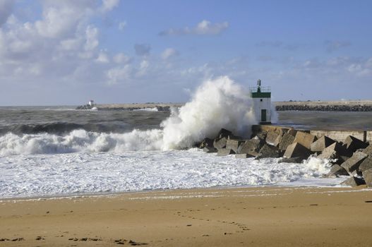 Big wave on a blocks jetty with a little lighthouse