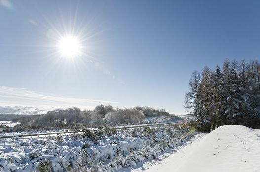 Winter landscape with a blue sky and lot of snow and also with a motorway