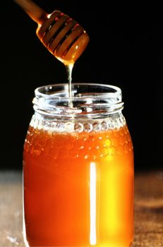 Golden Honey dripping from a wood stick pouring. stock photo