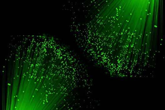 Close up capturing the ends of two groups of illuminated vibrant green fibre optic light strands against a black background.